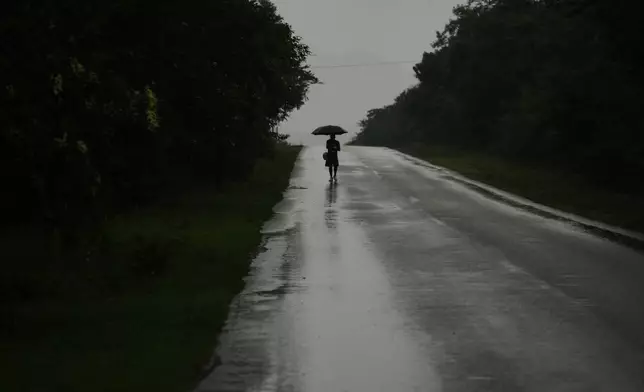 A man walks in the rain before the arrival of Hurricane Melissa in Canizo, a community in Santiago de Cuba, Tuesday, Oct. 28, 2025. (AP Photo/Ramon Espinosa)