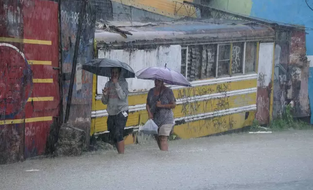People wade through a street flooded by rains caused by Tropical Storm Melissa in Santo Domingo, Dominican Republic, Friday, Oct. 24, 2025. (AP Photo/Ricardo Hernandez)