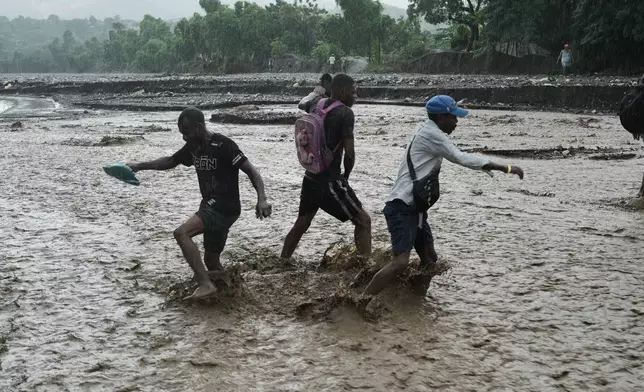 Residents wade through a flooded stream in the aftermath of Hurricane Melissa in Petit-Goave, Haiti, Thursday, Oct. 30, 2025. (AP Photo/Odelyn Joseph)