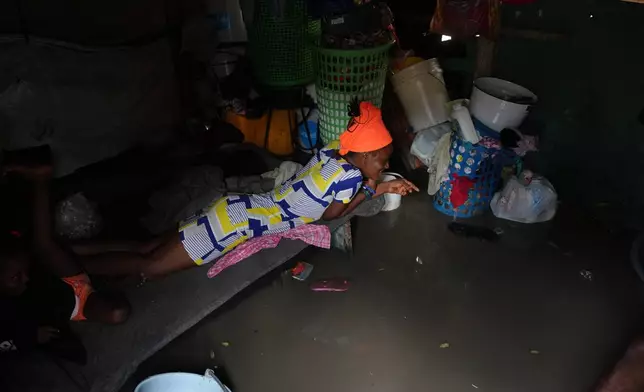 A woman lies inside a shack flooded by rain brought by Hurricane Melissa at a shelter for families displaced by gang violence in Port-au-Prince, Haiti, Wednesday, Oct. 29, 2025. (AP Photo/Odelyn Joseph)