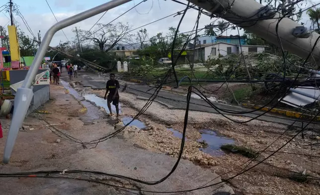 Residents walk through Santa Cruz, Jamaica, Wednesday, Oct. 29, 2025, after Hurricane Melissa passed. (AP Photo/Matias Delacroix)