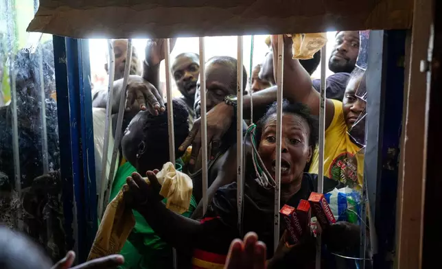 Residents crowd around a closed supermarket asking for supplies in Black River, Jamaica, Thursday, Oct. 30, 2025, in the aftermath of Hurricane Melissa. (AP Photo/Matias Delacroix)