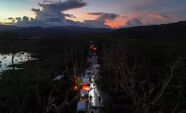A convoy carrying aid to Black River, which was hit by Hurricane Melissa, makes its way through Holland Bamboo, Jamaica, Wednesday, Oct. 29, 2025, where downed trees and debris partially block the road. (AP Photo/Matias Delacroix)