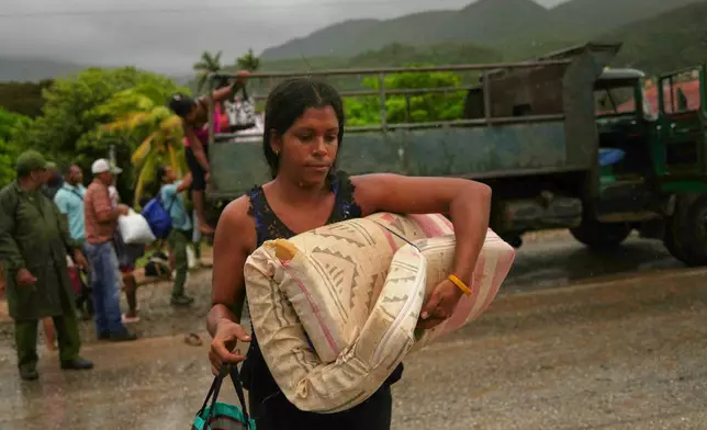 A woman carrying a mattress in the rain evacuates before the arrival of Hurricane Melissa in Cañizo, a community in Santiago de Cuba, Tuesday, Oct. 28, 2025. (AP Photo/Ramón Espinosa)