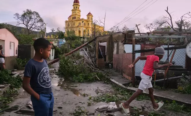 Boys walk in El Cobre, Cuba, in the aftermath of Hurricane Melissa on Wednesday, Oct. 29, 2025. (AP Photo/Ramon Espinosa)
