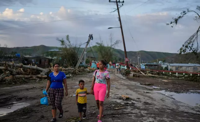 Residents walk in the aftermath of Hurricane Melissa in El Cobre, Cuba, Wednesday, Oct. 29, 2025. (AP Photo/Ramon Espinosa)