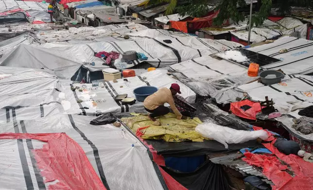 A man places plastic tarps over tents at a shelter for families displaced by gang violence during a break in the rain brought by Hurricane Melissa in Port-au-Prince, Haiti, Wednesday, Oct. 29, 2025. (AP Photo/Odelyn Joseph)