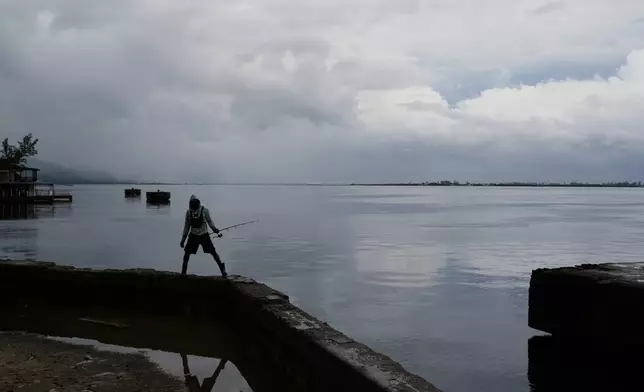 A man holds his fishing rod ahead of the forecast arrival of Hurricane Melissa in Kingston, Jamaica, Sunday, Oct. 26, 2025. (AP Photo/Matias Delacroix)