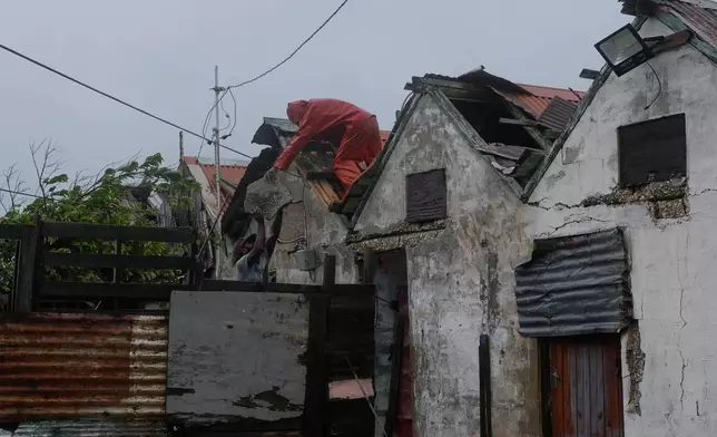 Men remove a loose section of roof in Kingston, Jamaica, as Hurricane Melissa approaches, Tuesday, Oct. 28, 2025. (AP Photo/Matias Delacroix)