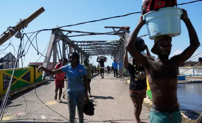 Residents leave Black River, Jamaica, Thursday, Oct. 30, 2025, after their homes were damaged by Hurricane Melissa. (AP Photo/Matias Delacroix)