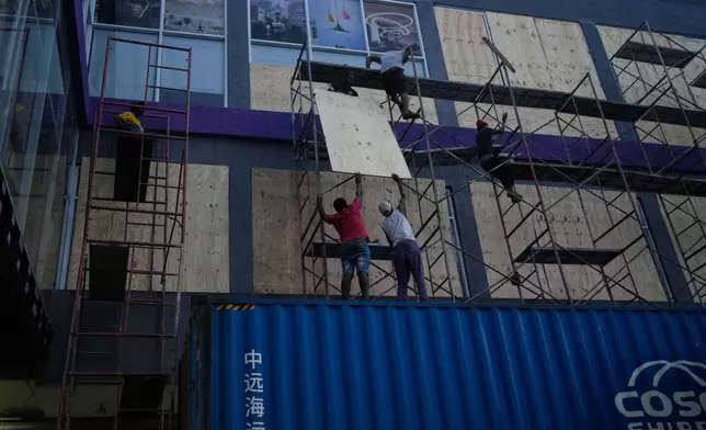 Workers board up shop windows ahead of Hurricane Melissa's forecast arrival in Kingston, Jamaica, Sunday, Oct. 26, 2025. (AP Photo/Matias Delacroix)