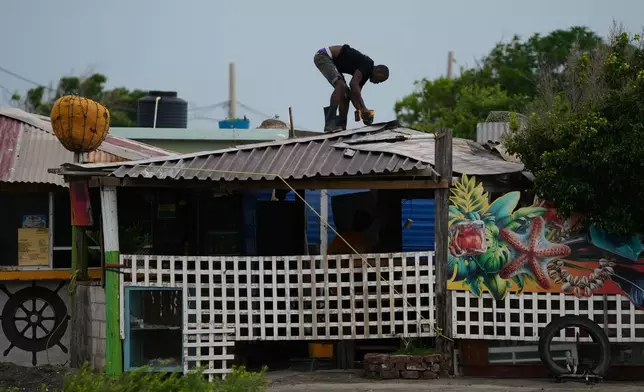 A man fortifies a roof ahead of the forecast arrival of Hurricane Melissa in Kingston, Jamaica, Sunday, Oct. 26, 2025. (AP Photo/Matias Delacroix)