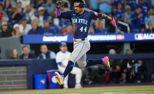 Seattle Mariners' Julio Rodríguez scores on an RBI single by teammate Josh Naylor against the Toronto Blue Jays during the first inning in Game 7 of baseball's American League Championship Series in Toronto, Monday, Oct. 20, 2025. (Frank Gunn/The Canadian Press via AP)