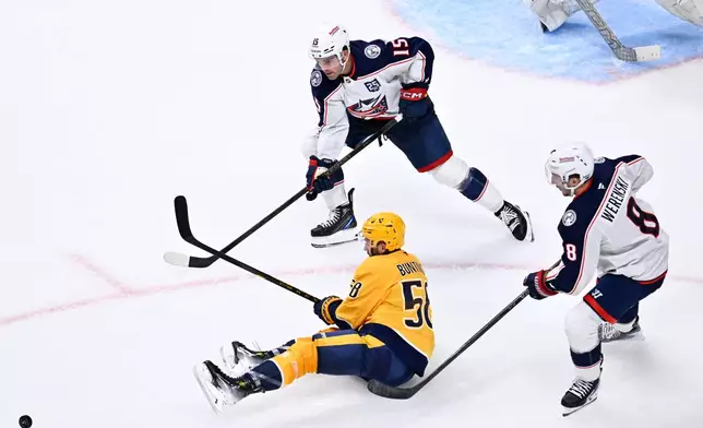 Nashville Predators left wing Michael Bunting (58) dishes the puck as Columbus Blue Jackets defenseman Dante Fabbro (15) and defenseman Zach Werenski (8) defend during the third period of an NHL hockey game Thursday, Oct. 9, 2025, in Nashville, Tenn. (AP Photo/John Amis)