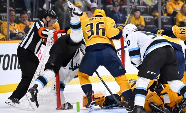 Utah Mammoth center Jack McBain is upended as Nashville Predators left wing Cole Smith (36) defends the goal during the first period of an NHL hockey game Saturday Oct. 11, 2025, in Nashville, Tenn. (AP Photo/John Amis)