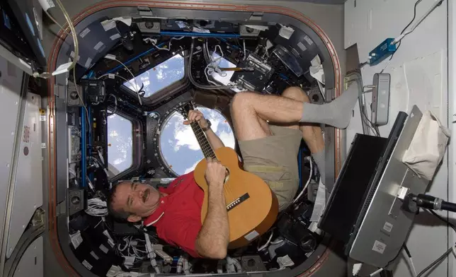 In this photo provided by NASA, Canadian astronaut Chris Hadfield plays guitar in the cupola module of the International Space Station on Dec. 25, 2012. (NASA via AP)