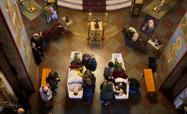 Relatives, colleagues and friends of two Ukrainian 43-year-old journalists Olena Hubanova, who worked under the pseudonym Alyona Gramova, and cameraman Yevhen Karmazin, who were killed on Thursday, Oct. 23, mourn over their coffins during a funeral service at St. Michael Monastery in Kyiv, Ukraine, Monday, Oct. 27, 2025. (AP Photo/Efrem Lukatsky)