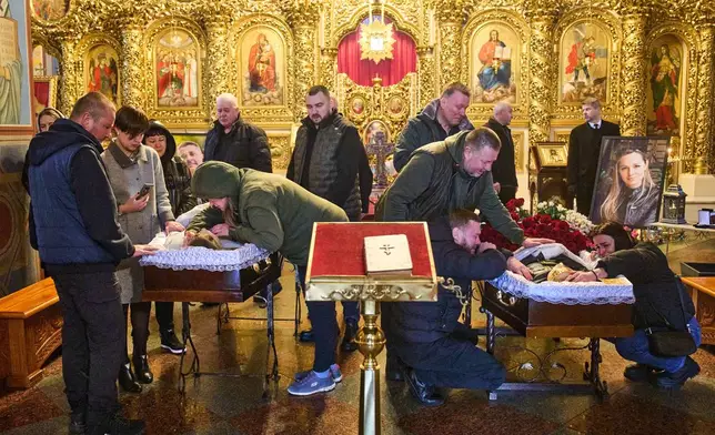 Relatives, colleagues and friends of two Ukrainian 43-year-old journalists Olena Hubanova, who worked under the pseudonym Alyona Gramova, and cameraman Yevhen Karmazin, who were killed on Thursday, Oct. 23, when a Russian Lancet drone hit their vehicle in Ukraine's Kramatorsk around 20 kilometres from the front line, mourn over their coffins during a funeral service at St. Michael Monastery in Kyiv, Ukraine, Monday, Oct. 27, 2025. (AP Photo/Efrem Lukatsky)