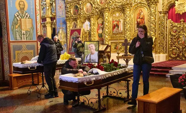Relatives, colleagues and friends of two Ukrainian 43-year-old journalists Olena Hubanova, who worked under the pseudonym Alyona Gramova, and cameraman Yevhen Karmazin, who were killed on Thursday, Oct. 23, when a Russian Lancet drone hit their vehicle in Ukraine's Kramatorsk around 20 kilometres from the front line, mourn over their coffins during a funeral service at St. Michael Monastery in Kyiv, Ukraine, Monday, Oct. 27, 2025. (AP Photo/Efrem Lukatsky)