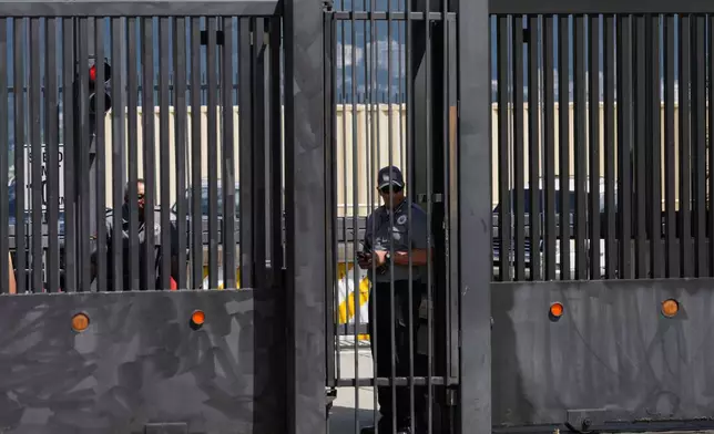 Security officers stand behind the main gate of the United States embassy in Caracas, Venezuela, Monday, Oct. 27, 2025. (AP Photo/Ariana Cubillos)
