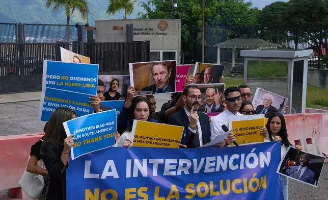 Gabriel Cabrera, president of the Venezuelan Youth Center for Democracy, gives a statement outside of the U.S. embassy with members of the organization holding signs that read in Spanish "Intervention is not the solution," in reference to U.S. warships operating in the Caribbean, in Caracas, Venezuela, Monday, Oct. 27, 2025. (AP Photo/Ariana Cubillos)