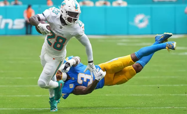 Miami Dolphins running back De'Von Achane, left, breaks free from Los Angeles Chargers safety Derwin James Jr. (3) during the first half of an NFL football game Sunday, Oct. 12, 2025, in Miami Gardens, Fla. (AP Photo/Lynne Sladky)
