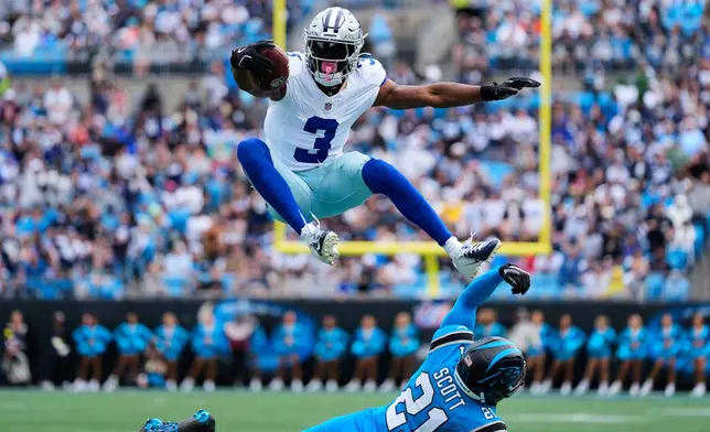 Dallas Cowboys wide receiver George Pickens (3) leaps over Carolina Panthers safety Nick Scott (21) after catching a pass in the first half of an NFL football game, Sunday, Oct. 12, 2025, in Charlotte, N.C. (AP Photo/Erik Verduzco)
