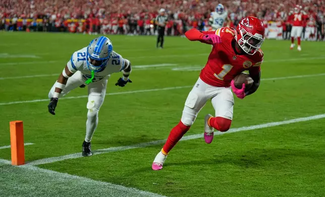 Kansas City Chiefs wide receiver Xavier Worthy (1) scores past Detroit Lions cornerback Amik Robertson (21) during the first half of an NFL football game Sunday, Oct. 12, 2025, in Kansas City, Mo. (AP Photo/Charlie Riedel)