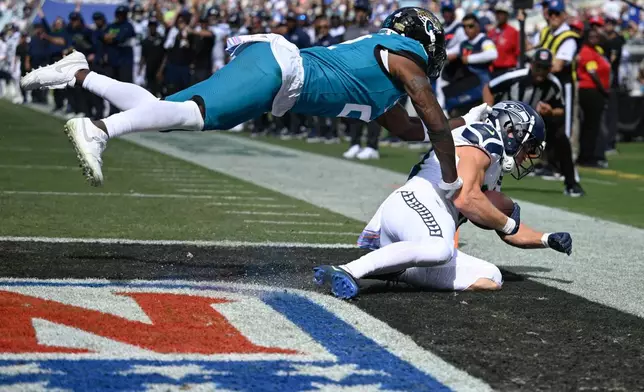 Seattle Seahawks wide receiver Cooper Kupp, right, catches a pass for a touchdown as Jacksonville Jaguars cornerback Jourdan Lewis defends during the second half of an NFL football game Sunday, Oct. 12 2025, in Jacksonville, Fla. (AP Photo/Phelan M. Ebenhack)
