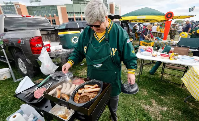 Mary Schroeder, of Morgan, Wis, cooks before an NFL football game between the Green Bay Packers and the Cincinnati Bengals, Sunday, Oct. 12, 2025, in Green Bay, Wis. (AP Photo/Mike Roemer)