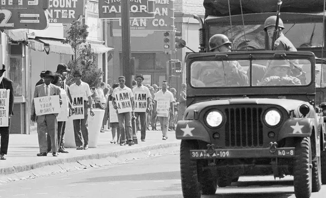 FILE - Tennessee National Guard troopers in jeeps and trucks escort striking Memphis sanitation workers during a march through downtown Memphis, Tenn., March 30, 1968. (AP Photo, File)