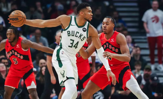 Milwaukee Bucks' Giannis Antetokounmpo (34) looks for options with pressure from Toronto Raptors' Scottie Barnes (4) during first half NBA basketball action in Toronto on Friday, Oct. 24, 2025. (Nick Iwanyshyn/The Canadian Press via AP)