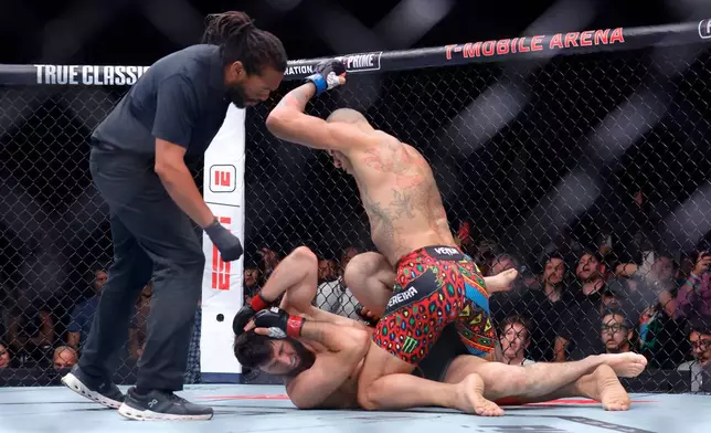 Alex Pereira, right, of Brazil, hits UFC light heavyweight champion Magomed Ankalaev, of Russia, as the referee looks on during the UFC 320 mixed martial arts bout Saturday, Oct. 4, 2025, in Las Vegas. (Steve Marcus/Las Vegas Sun via AP)