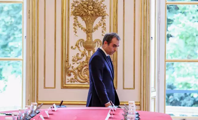 France's reappointed Prime Minister Sebastien Lecornu walks past a meeting table as he welcomes the newly-appointed members of his cabinet in Paris, Monday, Oct. 13, 2025. (Alain Jocard, Pool photo via AP)