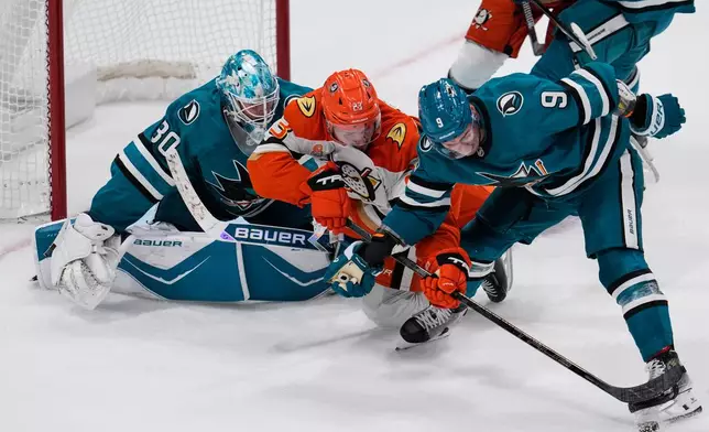 Anaheim Ducks center Mason McTavish (23) and San Jose Sharks defenseman Dmitry Orlov (9) compete for possession of the puck during the third period of an NHL hockey game, Saturday, Oct. 11, 2025, in San Jose, Calif. (AP Photo/Godofredo A. Vásquez)