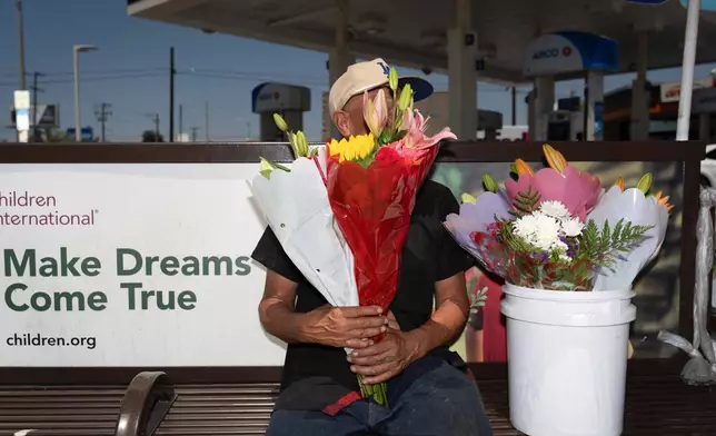 FILE - Flower vendor Jose, an immigrant from Mexico, sits for a photo with his face covered by flowers outside a gas station in Los Angeles, Friday, Aug. 8, 2025. (AP Photo/Jae C. Hong, File)