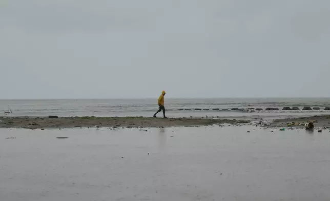 A man walks along the coastline ahead of the forecasted arrival of Hurricane Melissa in Old Harbour, Jamaica, Monday, Oct. 27, 2025. (AP Photo/Matias Delacroix)