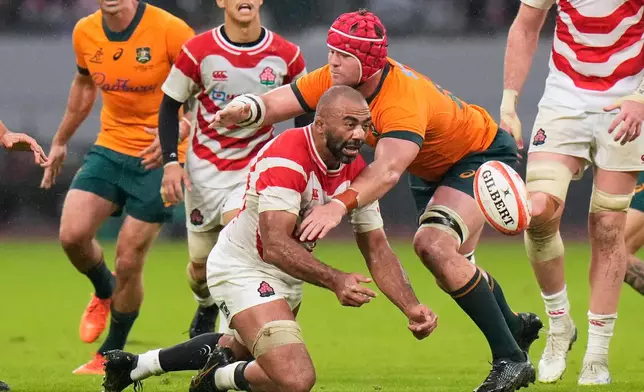 Japan's Michael Leitch, left, passes the ball as Australia's Harry Wilson attempts a tackle during a rugby test between the Wallabies and Japan in Tokyo, Saturday, Oct. 25, 2025. (AP Photo/Shuji Kajiyama)