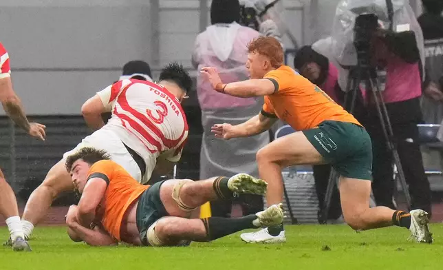 Japan's Shuhei Takeuchi runs through the tackle of Australia's Jeremy Williams and Tame Edmed, right, to score a try during a rugby test between the Wallabies and Japan in Tokyo, Saturday, Oct. 25, 2025. (AP Photo/Shuji Kajiyama)