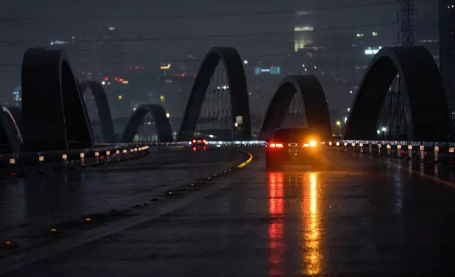 A car crosses under the dark the Sixth Street Viaduct downtown Los Angeles early morning Tuesday, Oct. 14, 2025. (AP Photo/Damian Dovarganes)