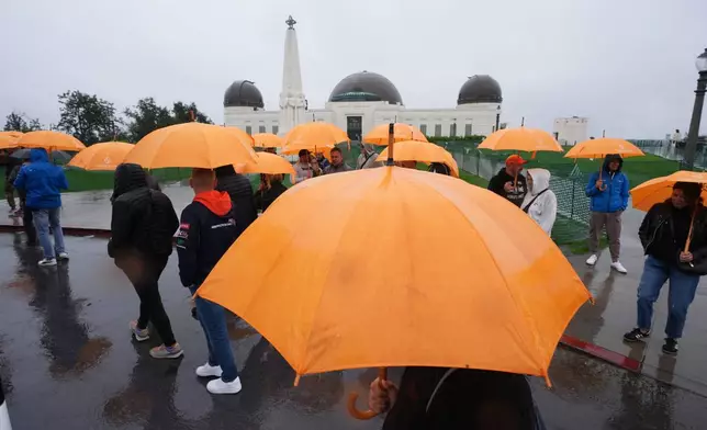 Tourists from Poland carry umbrellas as rain falls while visiting the Griffith Observatory Tuesday, Oct. 14, 2025, in Los Angeles. (AP Photo/Damian Dovarganes)