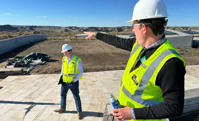 Theodore Roosevelt Presidential Library Foundation CEO Ed O'Keefe, right, points to the distance atop the roof of the library Tuesday, Oct. 7, 2025, near Medora, N.D. Seen at left is Foundation Chief Communications Officer Matt Briney. (AP Photo/Jack Dura)