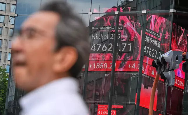 A person stand in front of an electronic stock board showing Japan's Nikkei index at a securities firm Monday, Oct. 6, 2025, in Tokyo. (AP Photo/Eugene Hoshiko)