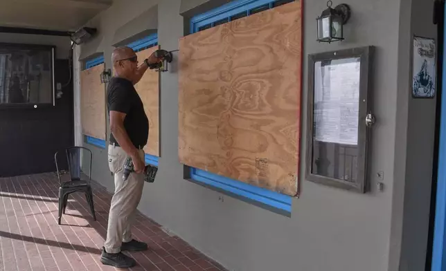 A man boards up his business' windows in preparation of Hurricane Imelda in Hamilton, Bermuda, Wednesday, Oct. 1, 2025. (AP Photo/Anthony Wade)