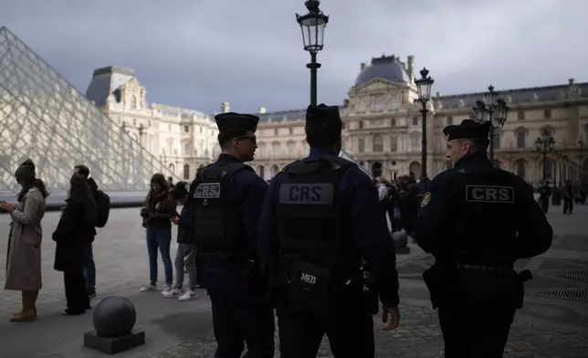 Riot police officers patrol as people queue to enter Le Louvre museum Monday, Oct. 27, 2025 in Paris. (AP Photo/Christophe Ena)