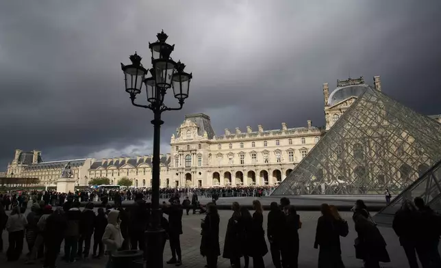 People queue to enter Le Louvre museum Monday, Oct. 27, 2025 in Paris. (AP Photo/Christophe Ena)