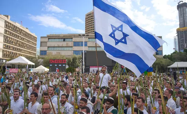 Covered in prayer shawls, men dance and hold the four items used as a symbol on the Jewish holiday of Sukkot, at a plaza known as hostages square following the announcement that Israel and Hamas have agreed to the first phase of a peace plan to pause the fighting in Gaza, in Tel Aviv, Israel, Friday, Oct. 10, 2025. (AP Photo/Ariel Schalit)