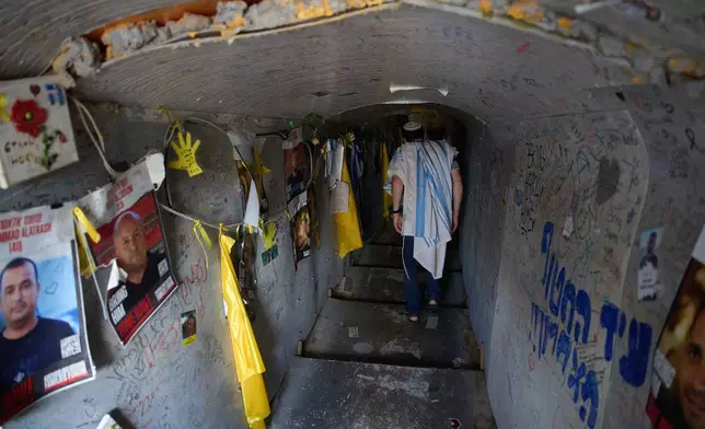 Covered in a prayer shawl, a man visits an installation simulating a tunnel in Gaza in an act of solidarity with hostages believed to be held underground by Hamas during the Jewish holiday of Sukkot, at a plaza known as hostages square, in Tel Aviv, Israel, Friday, Oct. 10, 2025. (AP Photo/Ariel Schalit)