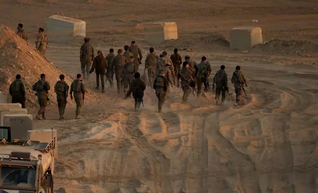 Israeli soldiers walk near the Israeli-Gaza border, as seen from southern Israel, Friday, Oct. 10, 2025, after Israel and Hamas have agreed to a pause in their war and the release of the remaining hostages. (AP Photo/Emilio Morenatti)
