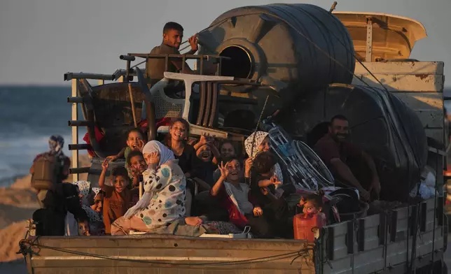 A displaced Palestinian family, rides on a truck loaded with water tanks, furniture and other belongings as they travel along the coastal road near Wadi Gaza in the central Gaza Strip, heading toward Gaza City, Friday, Oct. 10, 2025, after Israel and Hamas agreed to a pause in their war and the release of the remaining hostages. (AP Photo/Abdel Kareem Hana)
